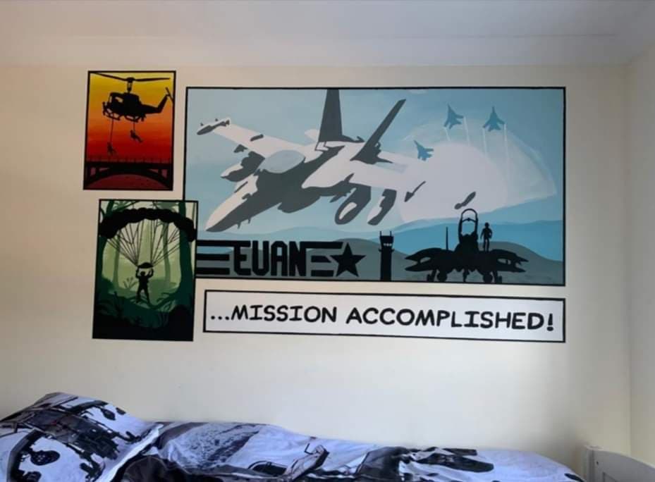 Custom hand-painted military and aviation wall mural in a child’s bedroom with personalised name and comic-style panels